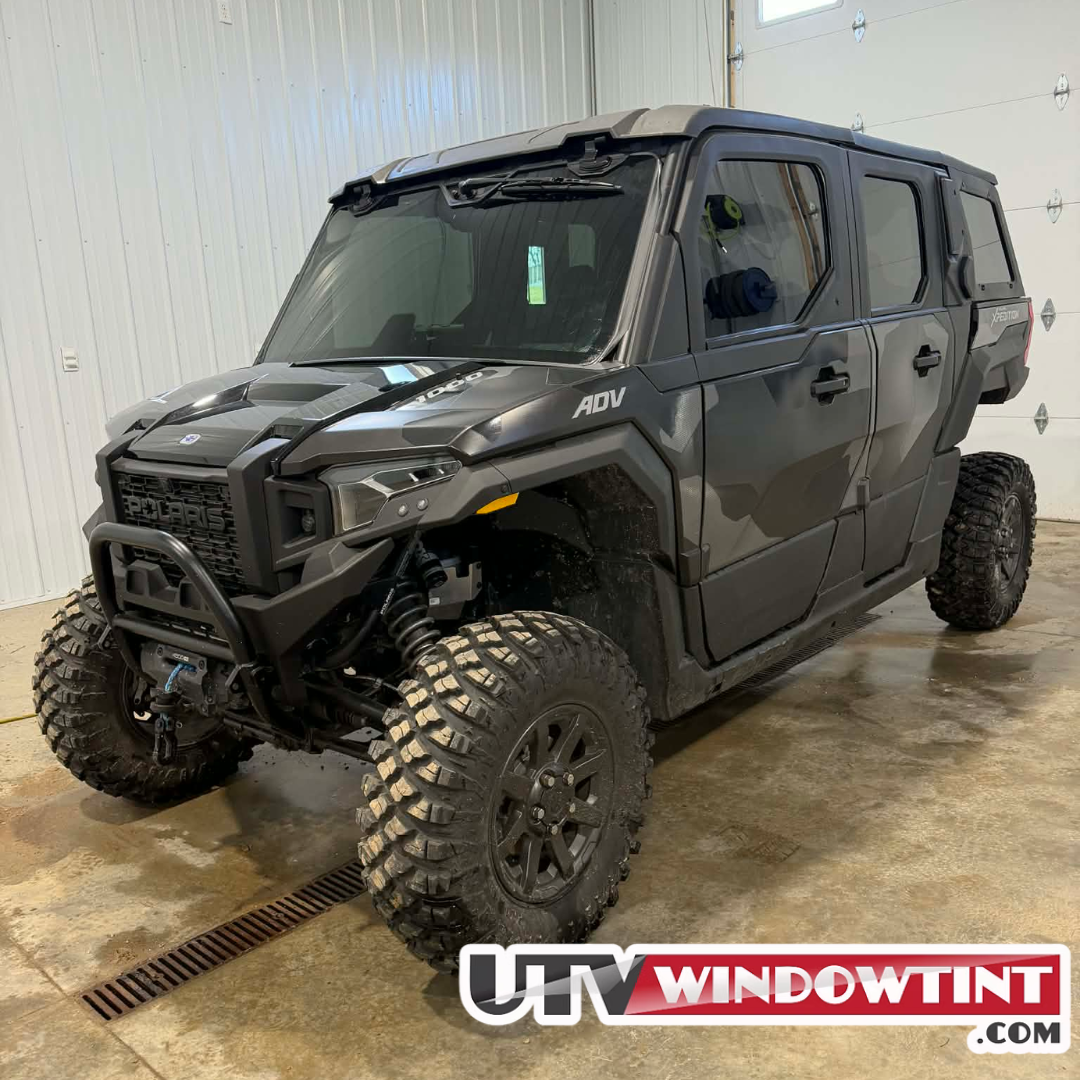 Polaris Xpedition ADV pre-cut window tint kit installed on a dark gray 4-door Polaris Xpedition ADV UTV, shown inside a garage, featuring tinted windshield and side door windows from UTVwindowtint.com